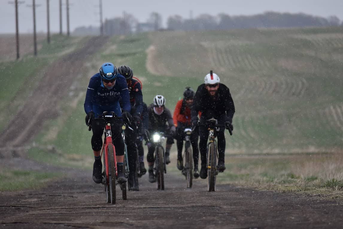 cyclists racing up a gravel hill in the snow