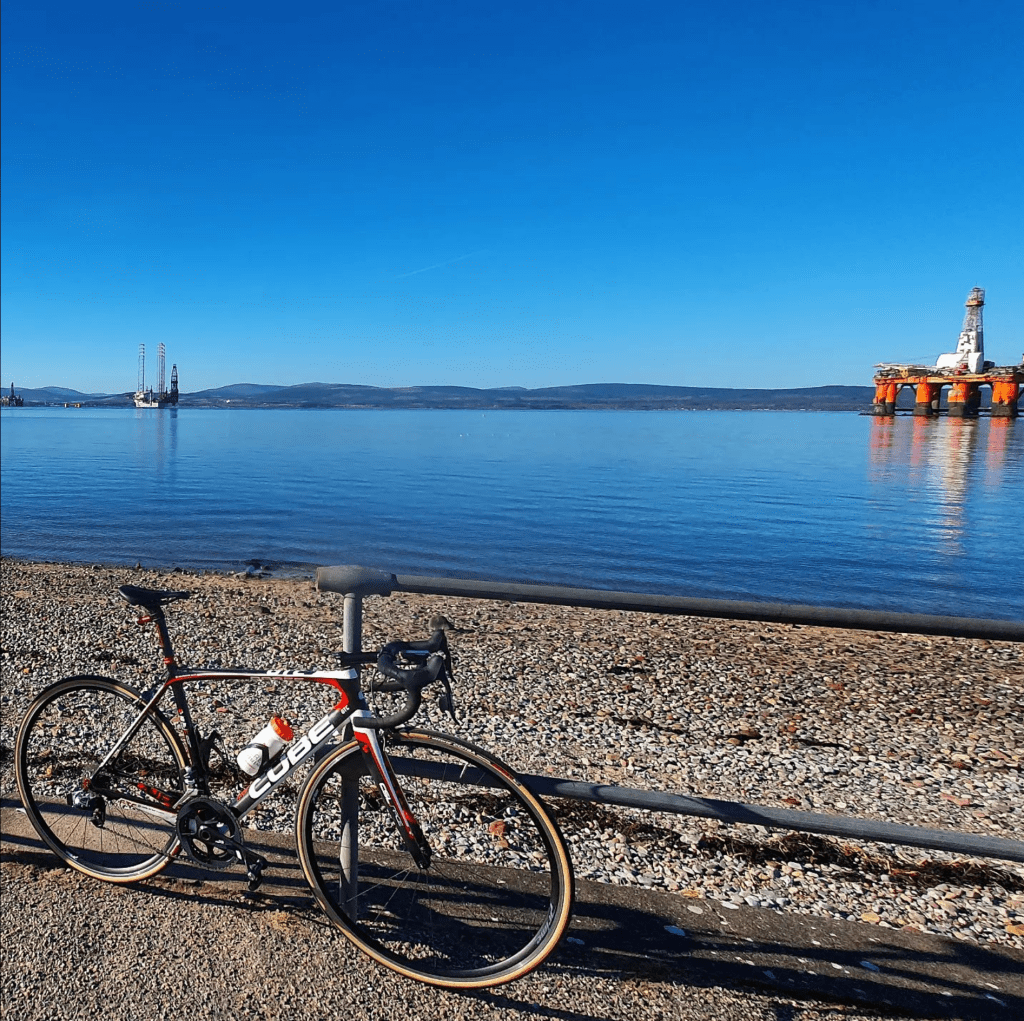 bike leaned up against a fence in front of water
