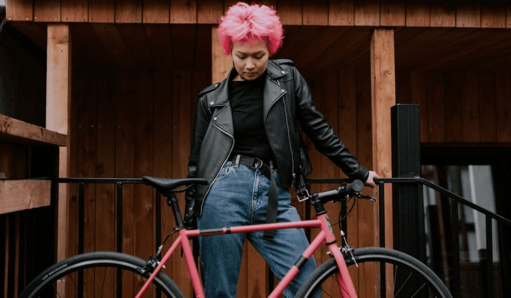 woman in genes standing with a bike